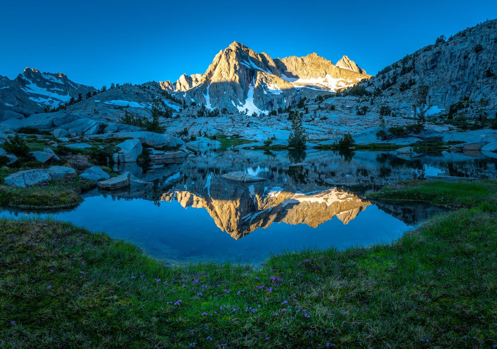 A granite peak reflecting in an alpine tarn in the Sabrina Basin of the Eastern Sierra.  Photo by Brock Dallman