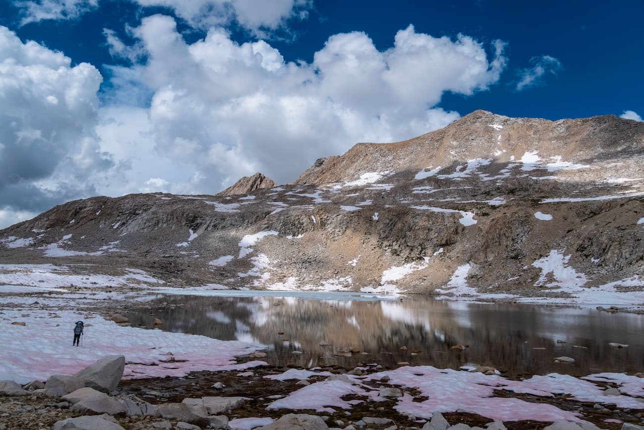 Sam Stych hiking over snow fields towards Muir Pass in Kings Canyon National Park.
