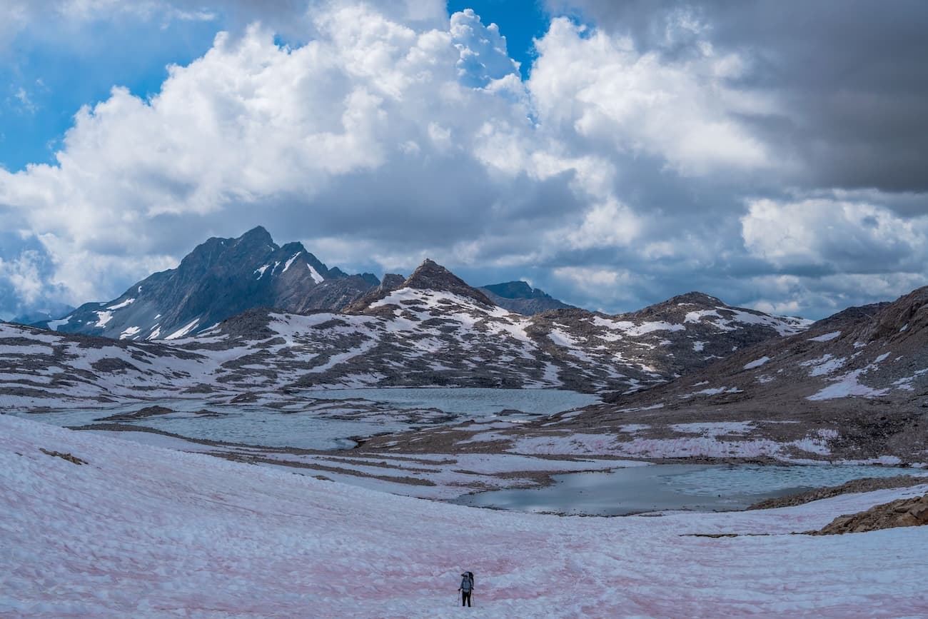 Sam Stych hiking over snow fields towards Muir Pass in Kings Canyon National Park.