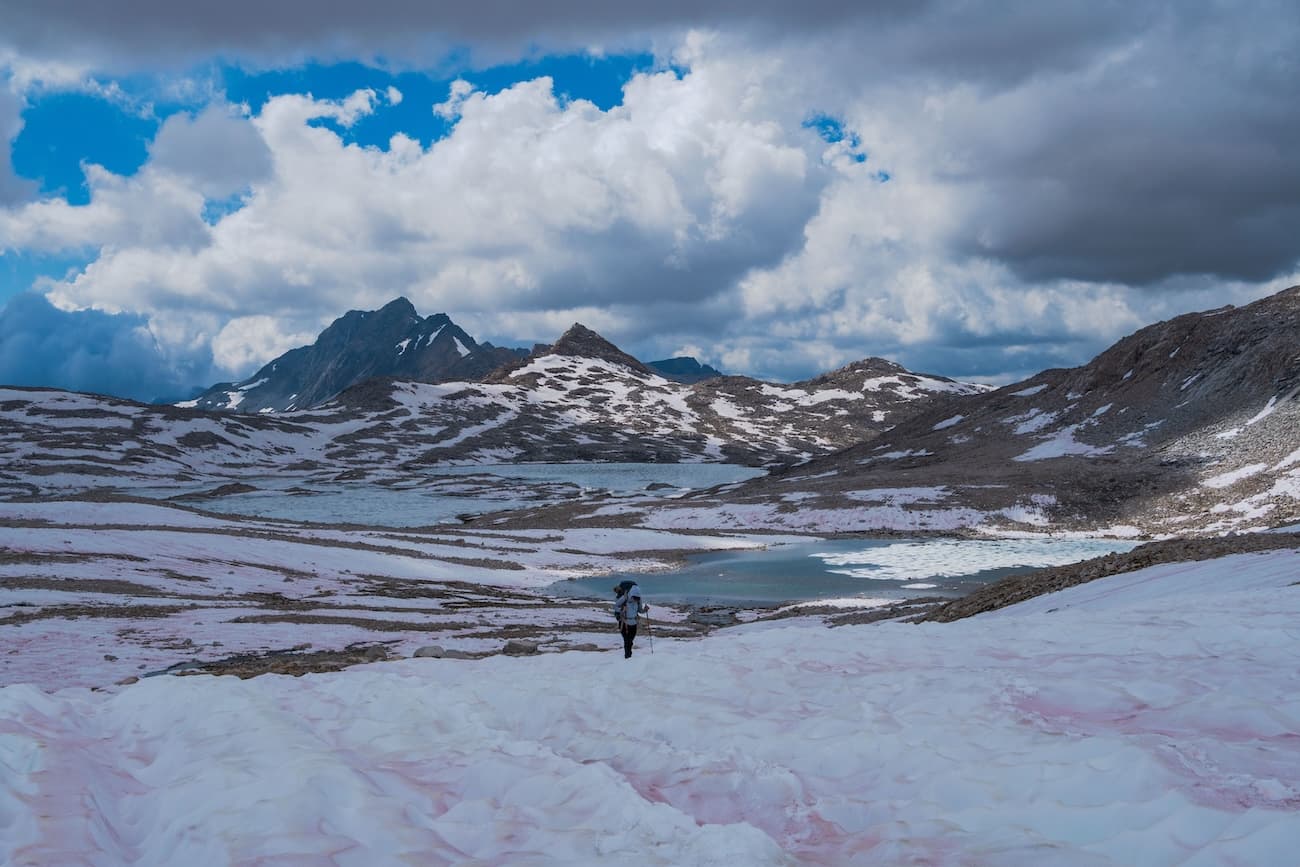 Sam Stych hiking over snow fields towards Muir Pass in Kings Canyon National Park.
