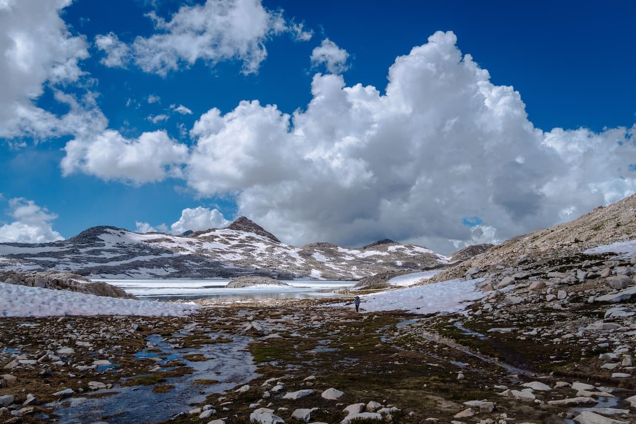 Sam hiking across snowfields with Wanda Lake in the background. Kings Canyon National Park